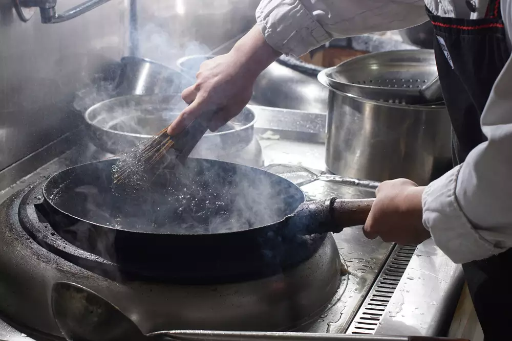 Cleaning wok with wooden sticks